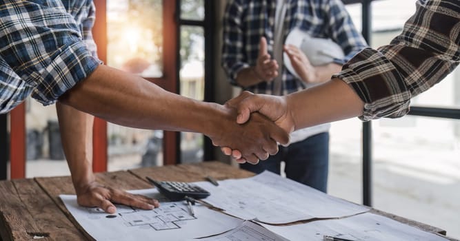 A team of engineers who successfully planned work on a modern home construction project shook hands and congratulated the team on their success..