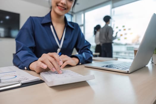 Close up Business woman using calculator and laptop for do math finance on wooden desk in office and business working background, tax, accounting, statistics and analytic research concept.