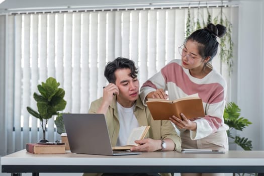 two confused and thoughtful young Asian college friends are looking at a laptop screen with a serious face and do not understand