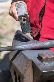 A blacksmith while working on an anvil is working on a piece of iron, an example of artistic blacksmithing