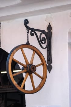 Wooden wheel on the wall of a country house, the historical designation of a wheelwright's workshop