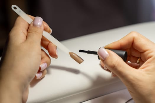 A manicurist applies gel nail polish to empty tips as a sample for future clients. Large range of gel polishes. Spa body care concept. Nail technician