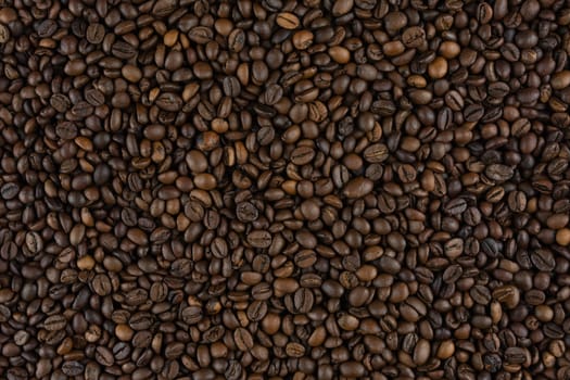 Close-up texture of roasted coffee beans forming a uniform background, rich in detail and natural tones, perfect for culinary or beverage-related concepts, no people.