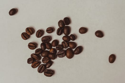 Minimalistic close-up of scattered roasted coffee beans arranged randomly on a clean white background.