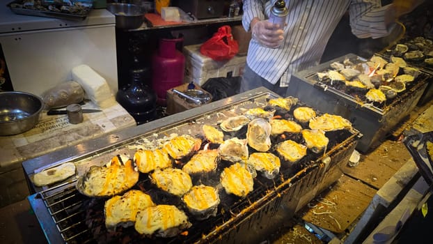 street vendor uses a torch flame to prepare delicious grilled oyster with flair and skill, showcasing the vibrant atmosphere of bustling night Thai markets. Good for recipe book