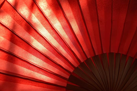 Close up of chinese red fan with sun glare. Chinese new year background.