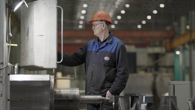 A focused worker in a safety helmet operates machinery in a well lit industrial setting, ensuring smooth operations. Stock Clip