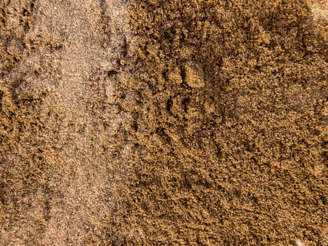 Close up of sandy beach texture with brown and golden hues.