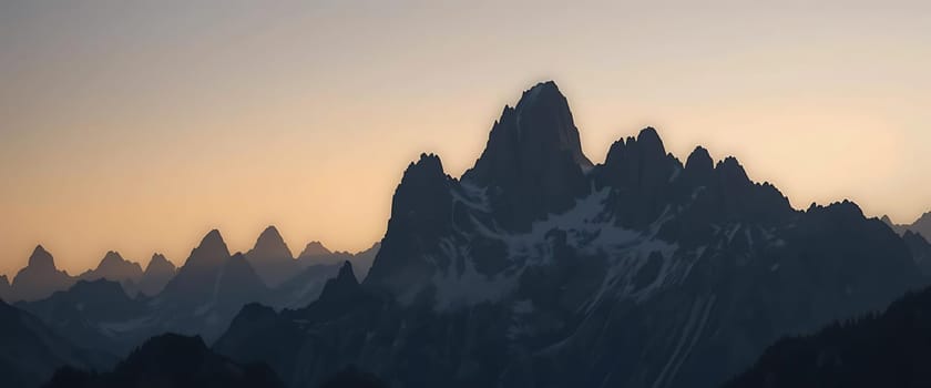 Jagged peaks pierce the twilight, a symphony of shadows and silence. The fading sun casts a golden whisper, as the lonely mountains stand sentinel against the night, evoking awe and solitude.