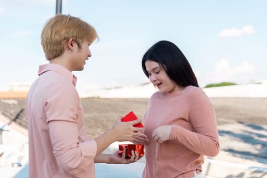 A couple shares a heartfelt moment on a rooftop exchanging Valentine gifts filled with love.