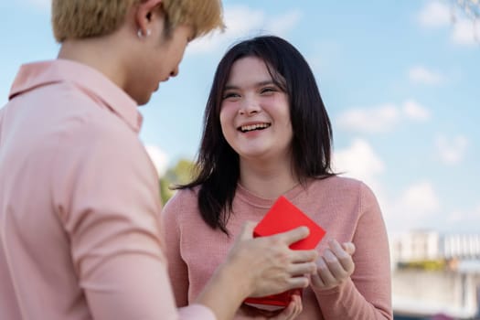 A couple shares a joyful moment during Valentine Day exchanging a heartfelt gift outdoors.