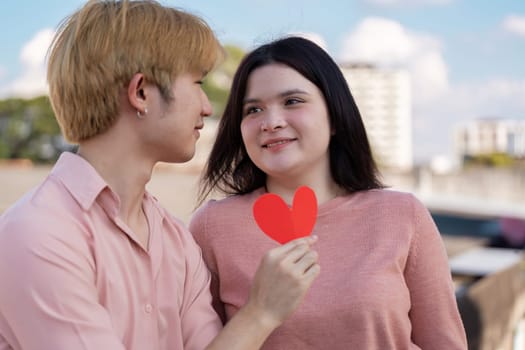 A couple shares their love on Valentine Day showcasing a sweet moment with a heart cutout in a beautiful outdoor setting.