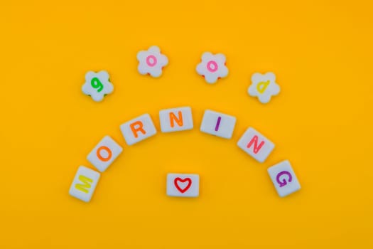 Cheerful "Good morning" spelled out with vibrant letters in a creative arc on a bright yellow background, featuring a heart symbol for positivity.