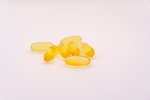 Group of yellow Omega-3 softgel capsules arranged on a clean white background, showcasing their translucent texture and vibrant color.