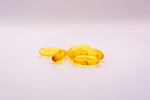 Close-up of Omega-3 softgel capsules with a glossy yellow finish, placed on a clean white background, emphasizing health and nutrition.