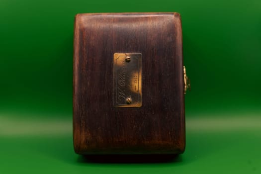 A vintage wooden box featuring a brass nameplate engraved with "W. Ottaway, London, 1915," set against a vibrant green background.