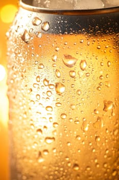 Close up of a cold beer can glistening with condensation, illuminated by a warm, inviting light