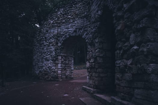 A weathered stone archway in ancient ruins surrounded by a dense forest, creating a mysterious and serene atmosphere.