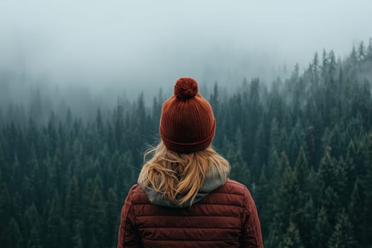 A woman wearing a red hat stands in front of a forest. Concept of solitude and peacefulness, as the woman is alone in the woods. The hat and the forest create a cozy and warm atmosphere