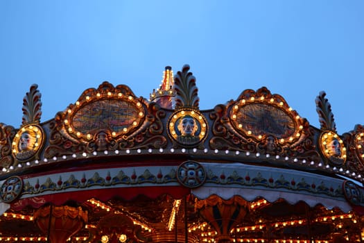 A beautifully illuminated carousel at dusk, showcasing its vintage charm, colorful scenes, and vibrant lights