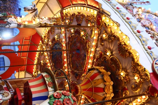Enjoy a stunning view of a beautifully decorated carousel with bright lights at a lively festive fairground