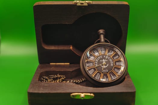 Vintage pocket watch marked "Marine Anchor 1912" with Roman numerals, displayed inside an open wooden case against a green background.