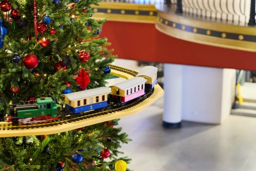 A beautifully vibrant Christmas tree brilliantly adorned with colorful decorations and a delightful toy train