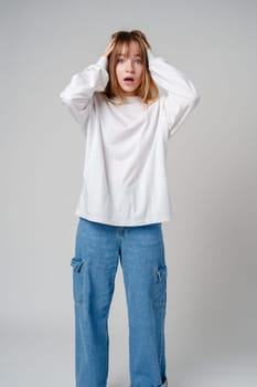 A young woman with light brown hair and blue eyes expresses surprise in a minimalist studio setting