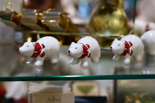 Three beautiful and adorable little white polar bear figurines, each adorned with cheerful red scarves, are on display