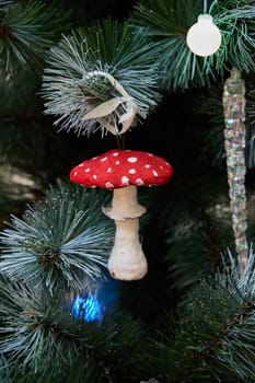 A whimsical red mushroom ornament is beautifully hanging on a vibrant and festive Christmas tree this season