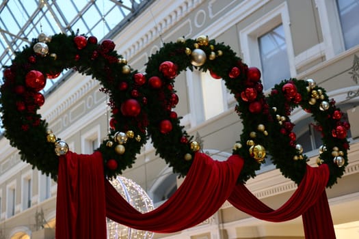 Beautifully arranged Christmas wreaths adorned with vibrant balls and ribbons create a festive atmosphere.