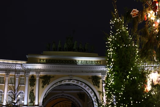 A beautifully illuminated tree stands gracefully beside a historic archway, joyfully celebrating the holiday season