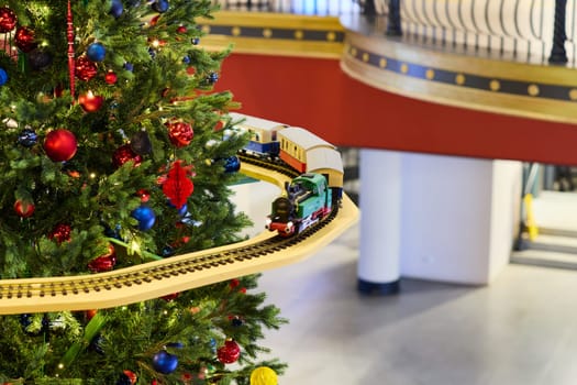 A joyful and festive scene featuring a beautifully decorated Christmas tree with a train circling around its base