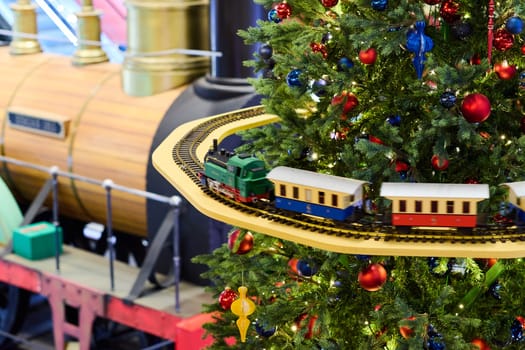 A whimsical train set is elegantly displayed on a lush and beautiful Christmas tree adorned with ornaments