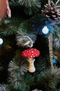 A red and white mushroom ornament hangs on a decorated Christmas tree, spreading festive holiday cheer