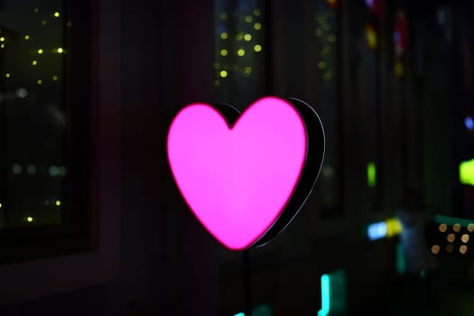A beautifully glowing pink heartshaped sign brings a delightful romantic vibe to the cityscape at night