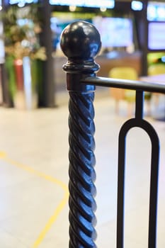 A sleek, stylish black railing post featuring a beautifully twisted design, situated in a contemporary indoor space