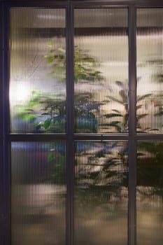 A beautifully blurred view through a misty window showcasing an array of vibrant green plants growing