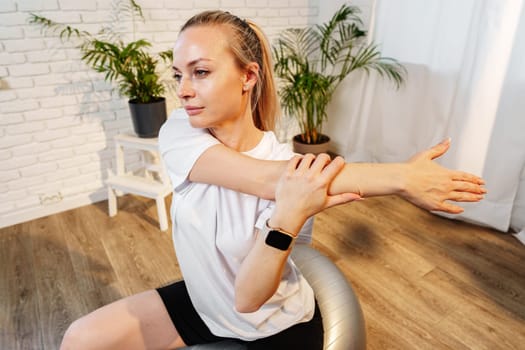 A woman stretching sideways in a bright, minimalist room with indoor plants