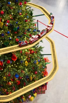 A cheerful and joyful toy train chugs around a beautifully decorated Christmas tree in a delightful festive scene