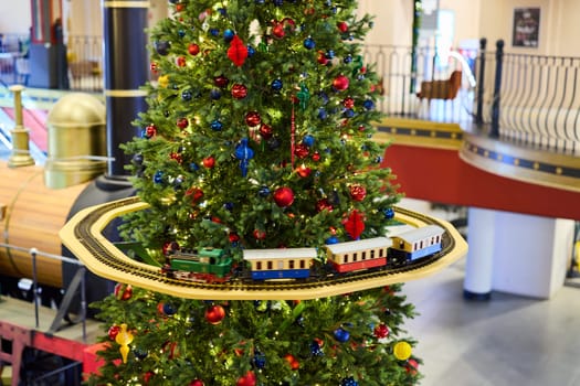 A beautifully decorated Christmas tree adorned with colorful ornaments featuring a train that runs around its base