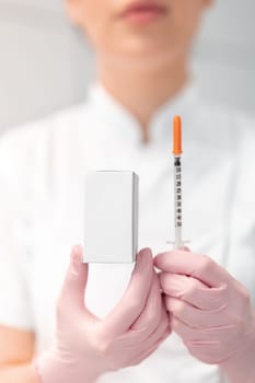 Unrecognizable female dermatologist holding injection syringe and medicine box with blank space in clinic. Anonymous cosmetologist in beauty spa salon.