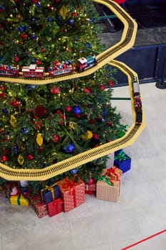 A Christmas tree that is beautifully adorned with decorations, showcasing a delightful toy train and vibrant presents
