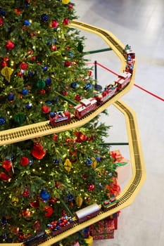 A beautifully festive Christmas tree, splendidly adorned with colorful ornaments and a charming toy train set
