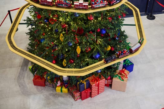 A stunningly decorated Christmas tree adorned with a cheerful train and bright, colorful gift boxes underneath it