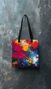 A tote bag adorned with a vibrant abstract design hangs on a textured gray wall in a contemporary art gallery, complementing the creative and artistic surroundings with its bold colors and modern aesthetic.