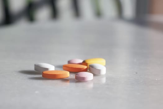 A colorful assortment of essential vitamins and medications spilled from a bottle onto the surface