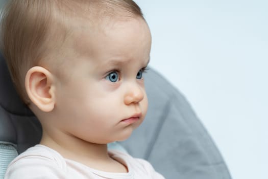 Thoughtful baby with bright blue eyes and a side profile