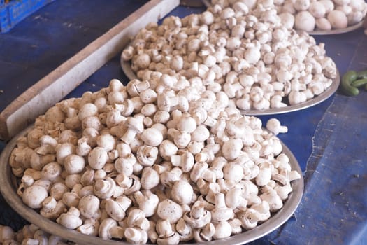 In a charming local market, bountiful white mushrooms are beautifully displayed in bowls for sale