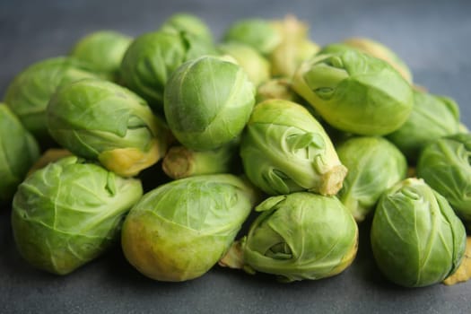 A vibrant stack of fresh Brussels sprouts elegantly displayed on a dark textured background